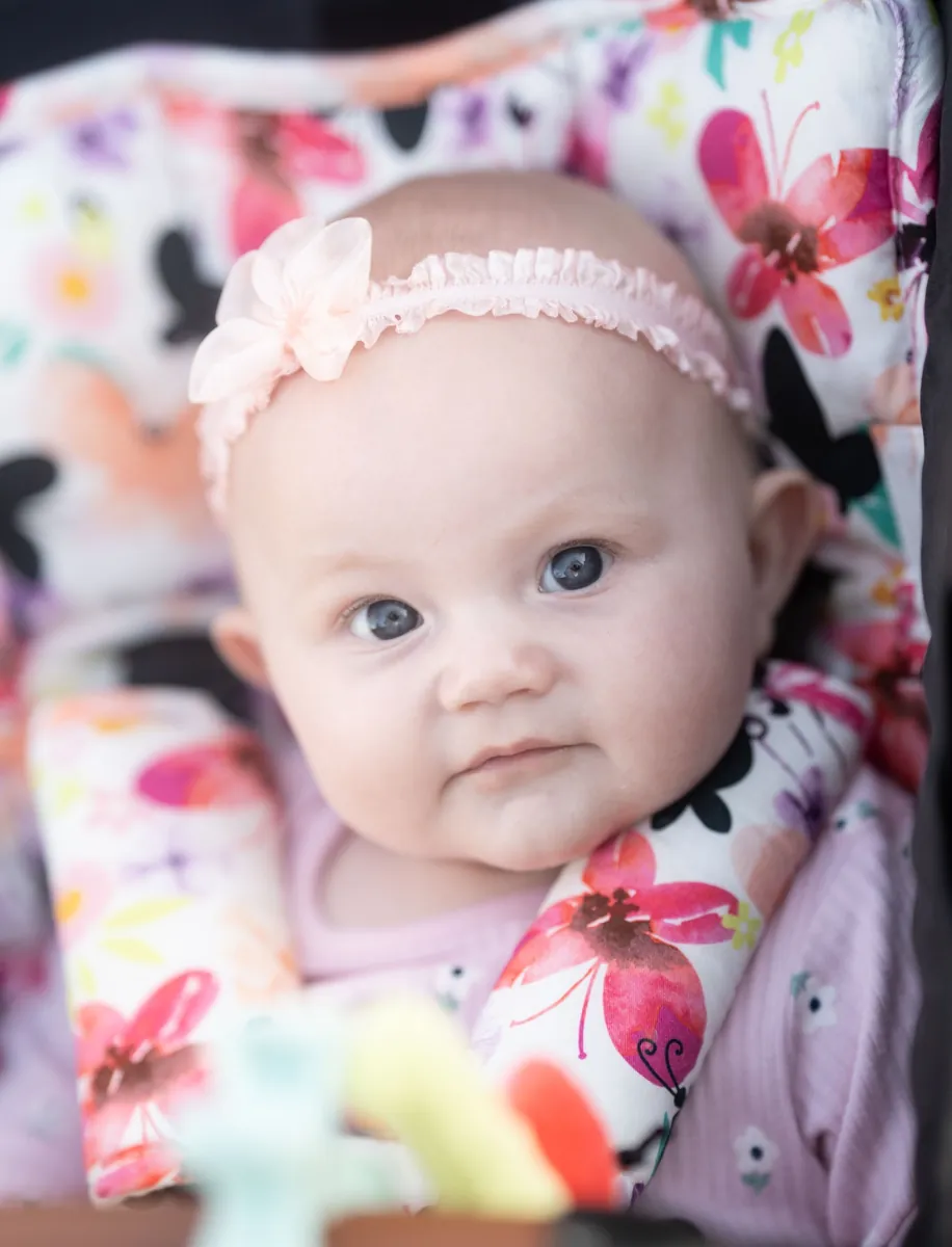 Baby with blue eyes sitting in a colourful floral seat, photographed by Little Star Photography in Brisbane QLD.