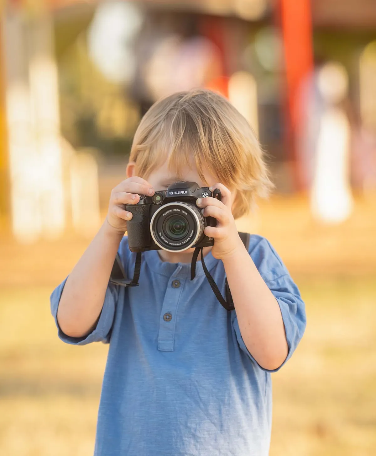 Young child holding a camera at a Brisbane QLD park, captured by Little Star Photography.