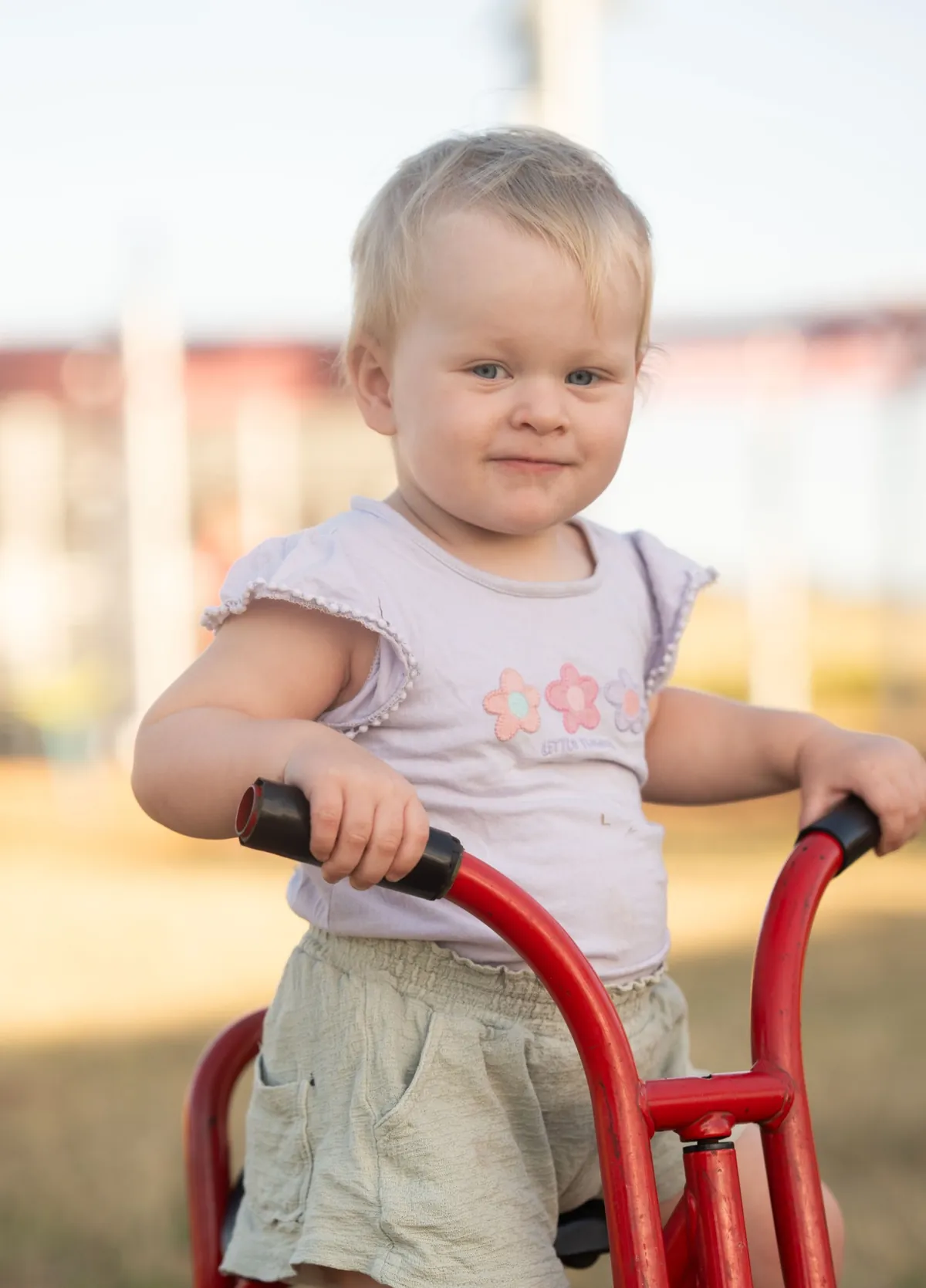 Toddler girl riding a red playground bike in a Brisbane park, photographed by Little Star Photography QLD.