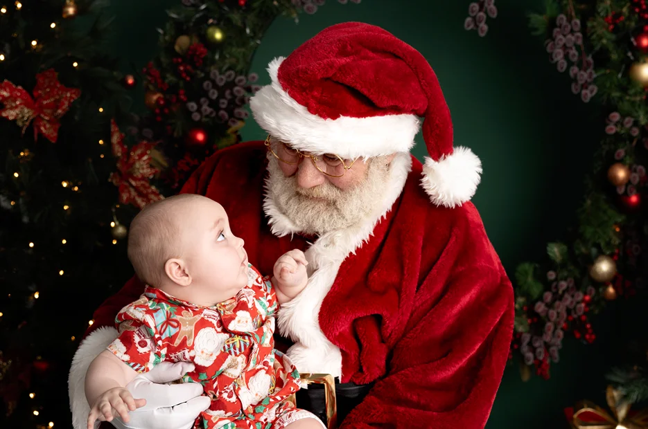 Baby sitting on Santa’s lap during a Santa baby Christmas portrait session.