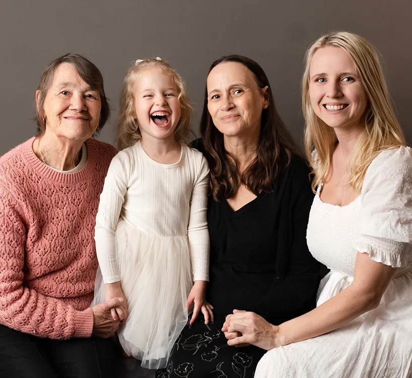 Grandmother, mother, child and daughter smiling together in a generations family portrait session.
